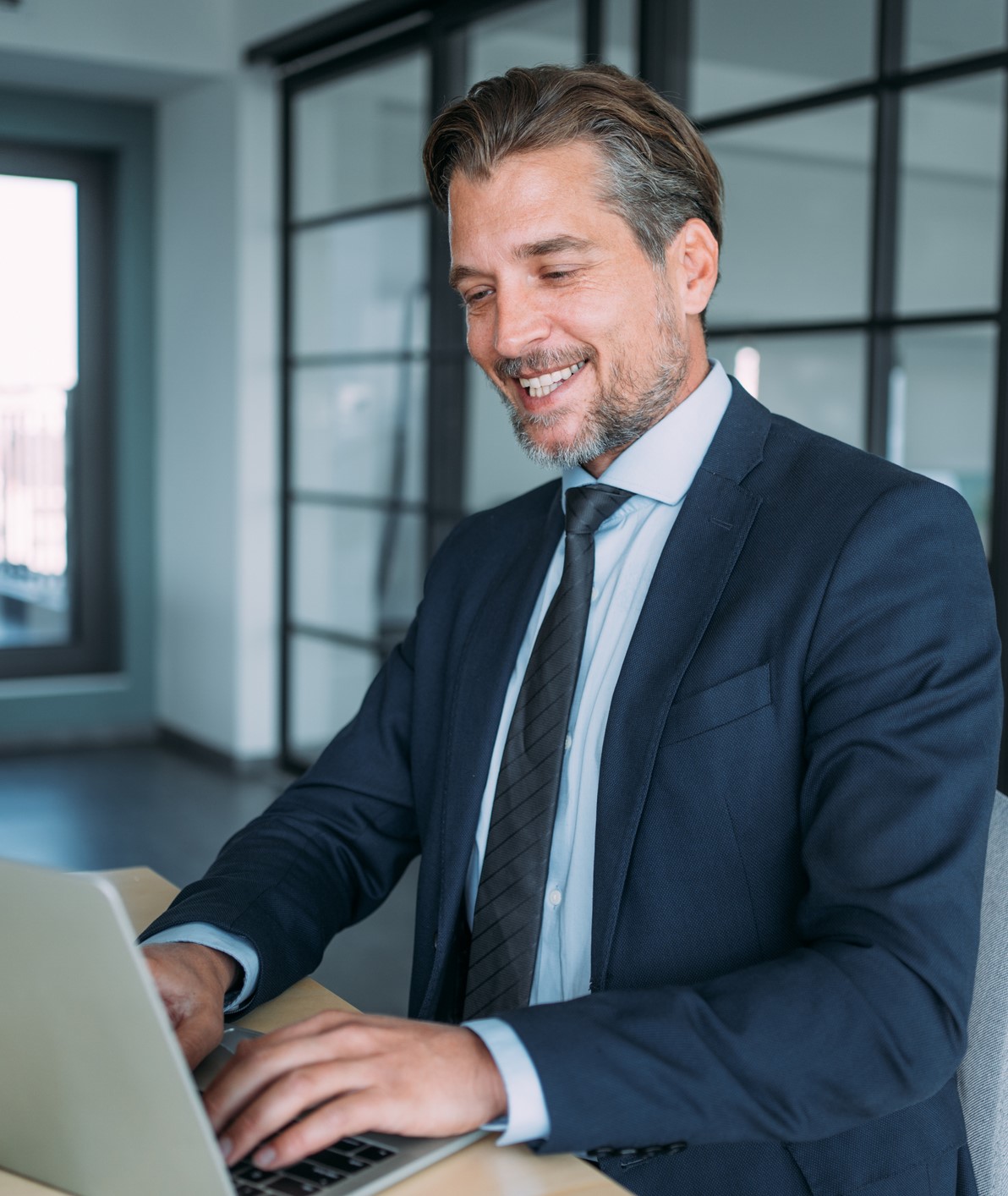 Homme d’affaires prospère dans un bureau moderne travaillant sur un ordinateur portable