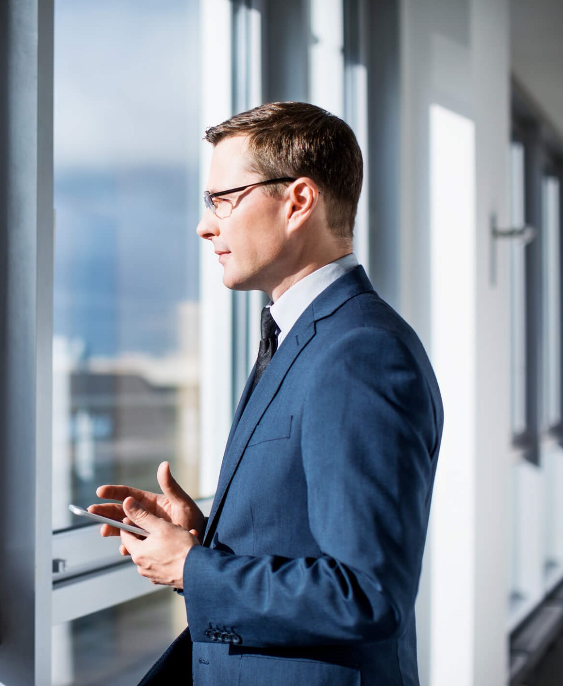 Homme d’affaires mature debout par la fenêtre dans le bureau