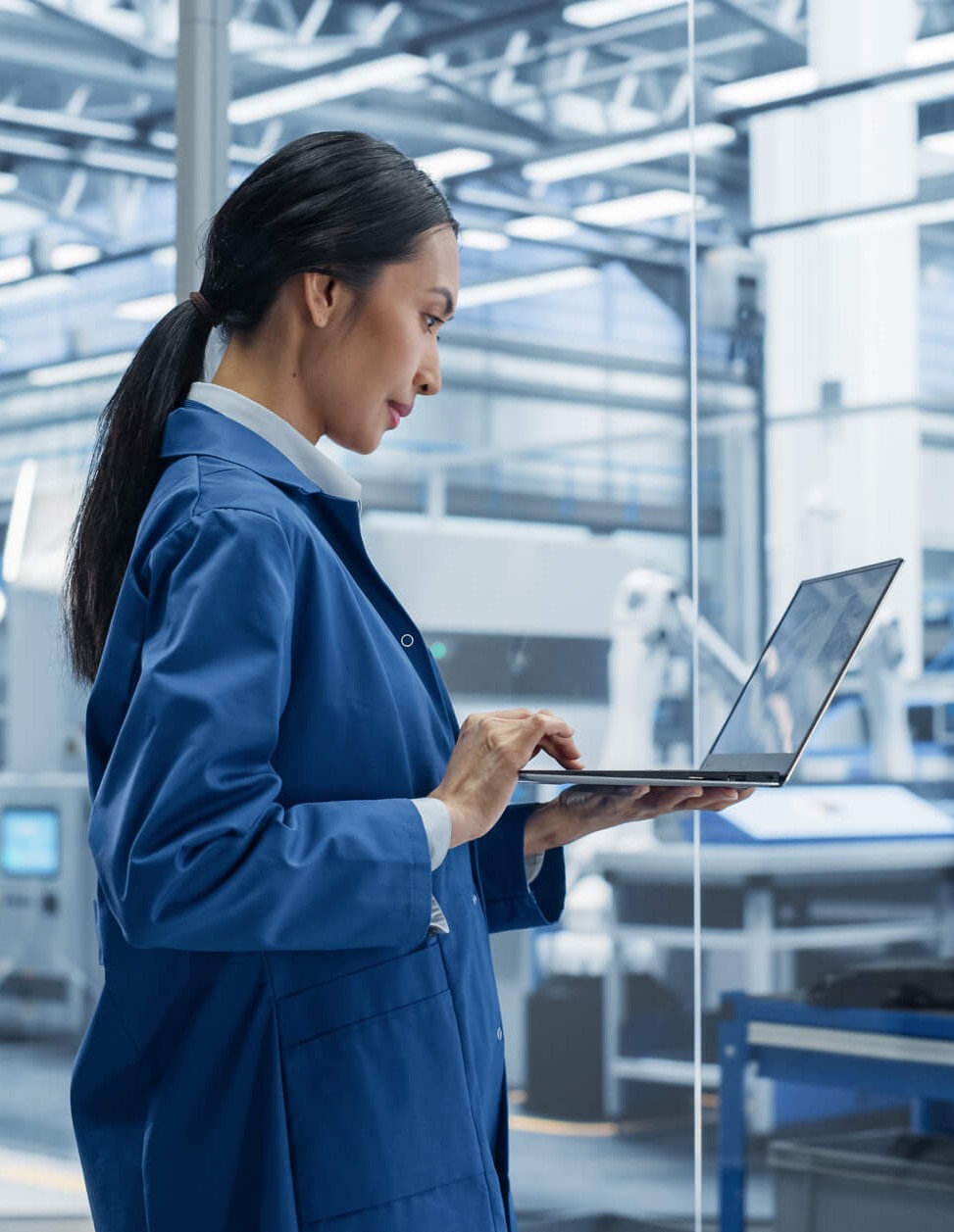 Ingénieur utilisant un ordinateur portable et regardant autour d’une installation d’usine avec de l’équipement produisant des composants électroniques modernes pour les besoins industriels avancés